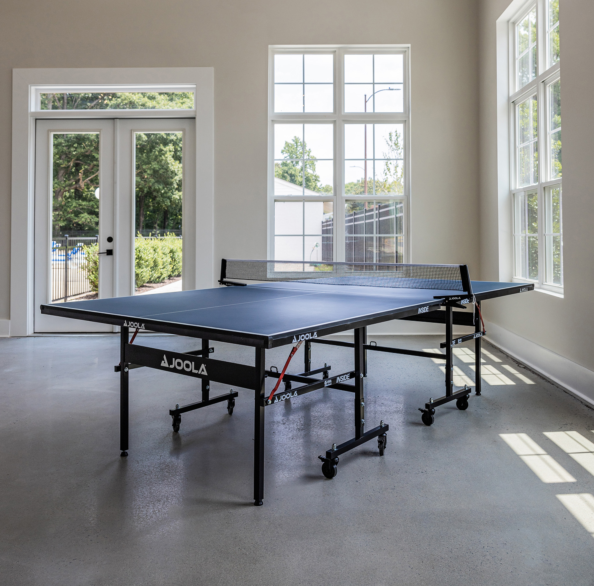 a blue ping pong table in a large room with windows